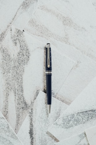 Close-up of a sleek black marble desk with a platinum pen and financial charts in the background.