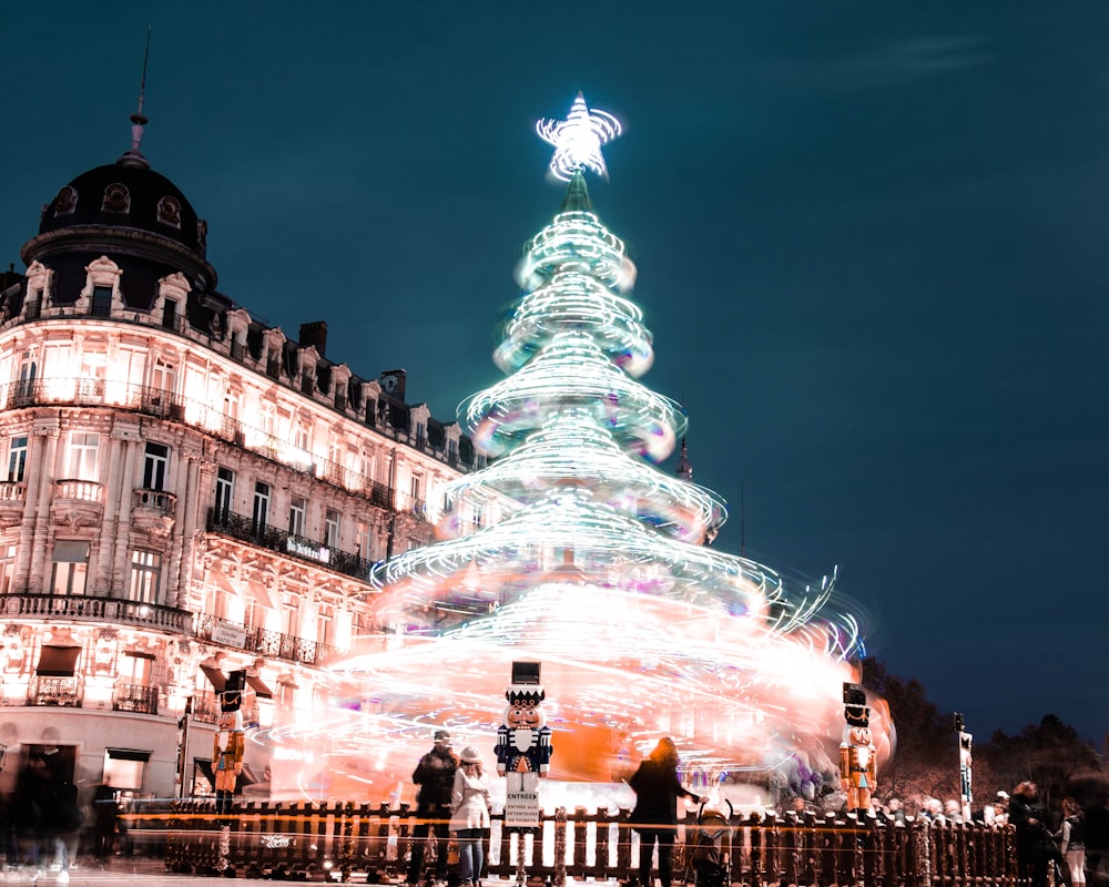 lighted Christmas tree beside lighted building at night