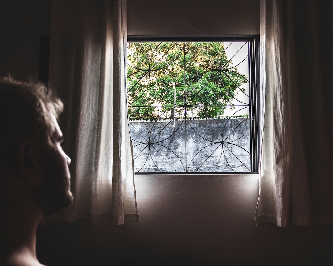 man in room with black window grill