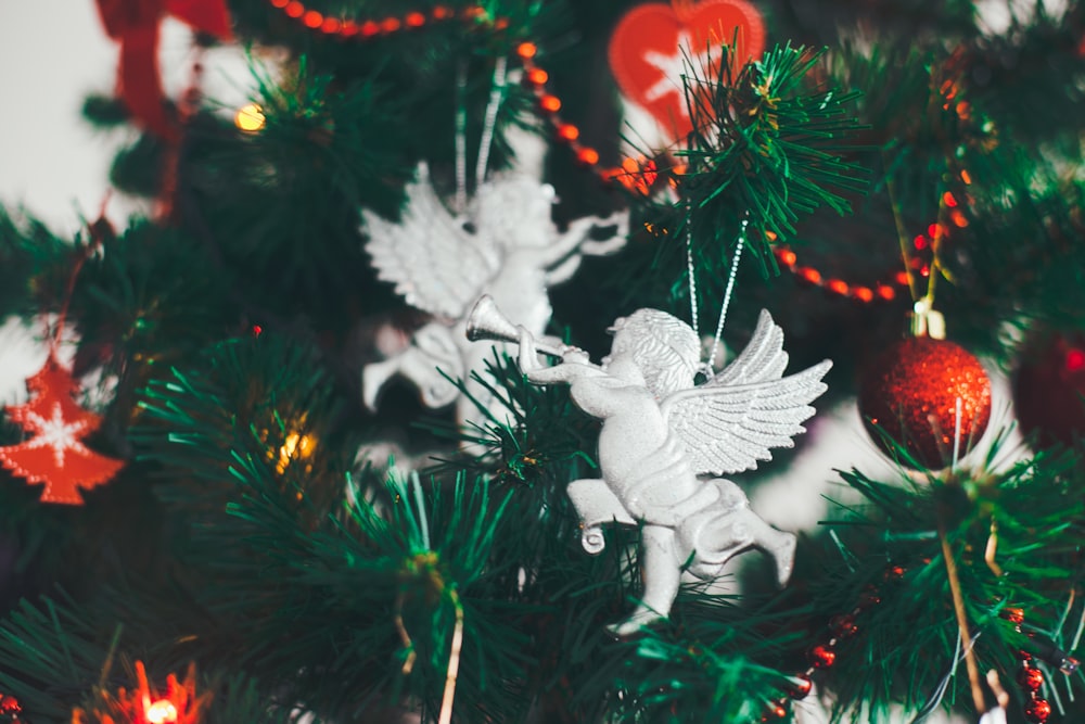 cherub playing trumpet and red ornaments hanging on Christmas tree