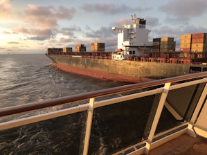Cargo ship loaded with containers sailing across the ocean at sunset