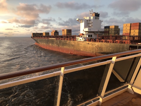 A cargo ship being loaded with containers at sunset.