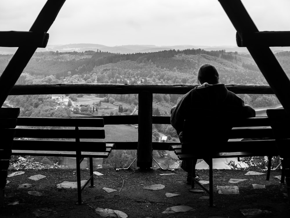 person sits on bench in front overview landscape