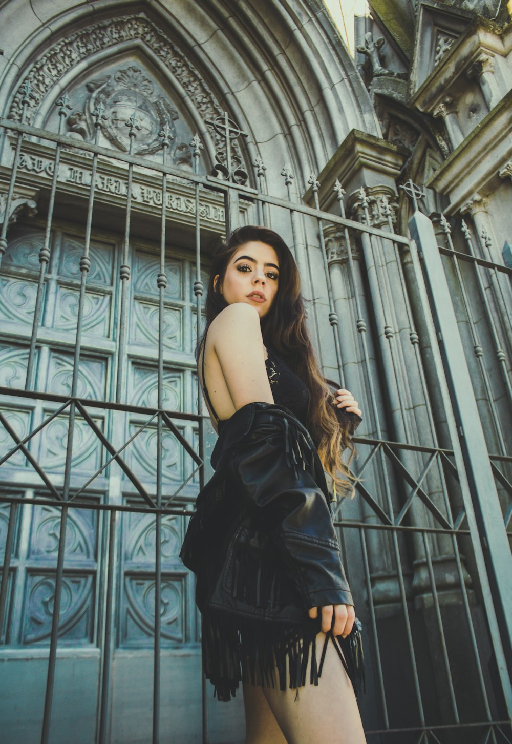 woman standing beside black gate wearing black leather jacket