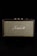 A vintage-style speaker with the brand name prominently displayed in white script against a woven fabric grille. The speaker casing has a textured black finish and gold control knobs on top, set against a black background.