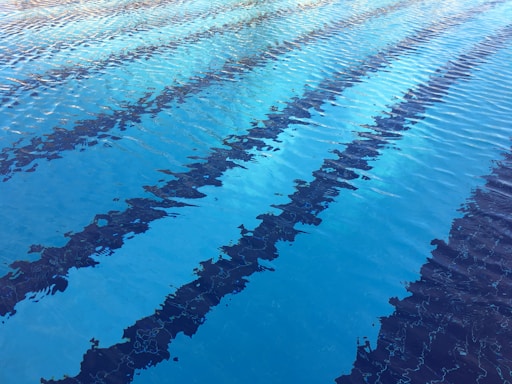 A swimming pool with clear blue water and several dark lane markers extending across its surface.