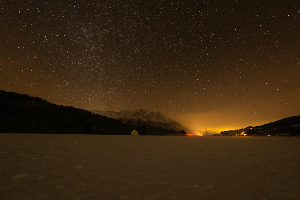 empty field near snow covered mountain during nighttime