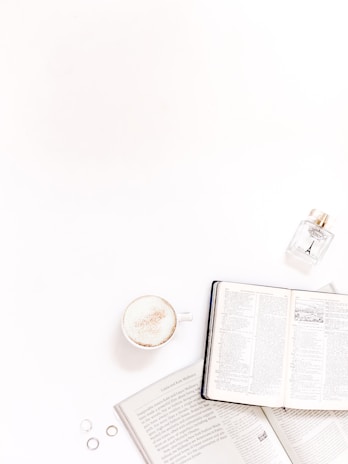 A sleek Rayhan perfume bottle placed beside an open book and a cup of tea on a quiet afternoon.