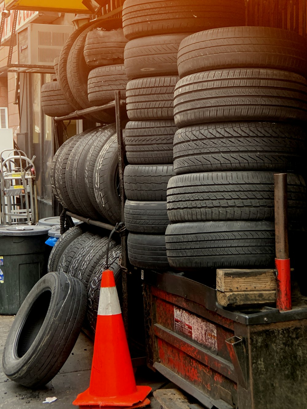 orange traffic cone near pile of vehicle tires