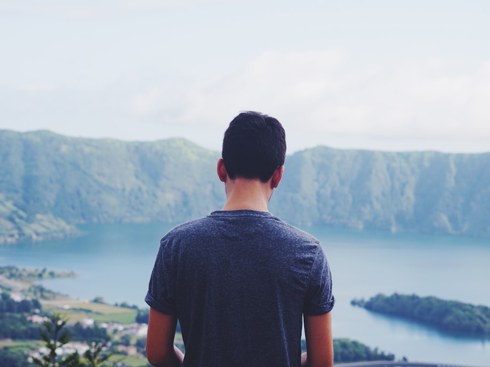 man standing outdoors with body of water at distance during daytime