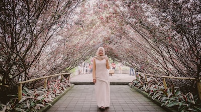 A serene outdoor scene with a woman in a modest, elegant abaya walking along a tree-lined path.