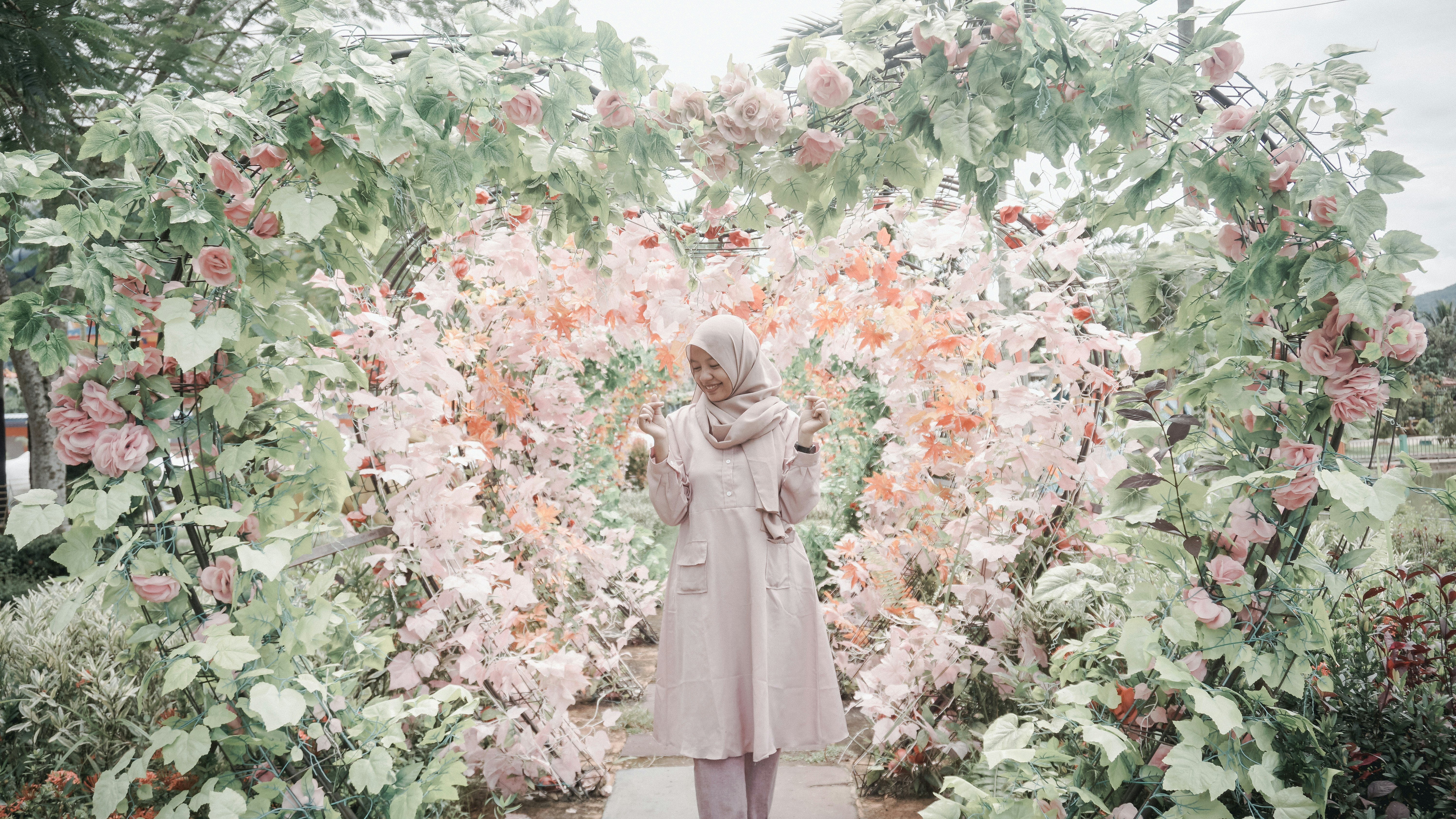 woman standing between heart framed flower garden \