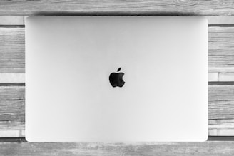 A silver laptop with a prominent fruit logo is placed on a wooden surface, showcasing a minimalist and sleek design.