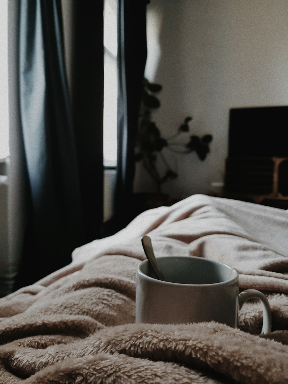 white ceramic mug on bed