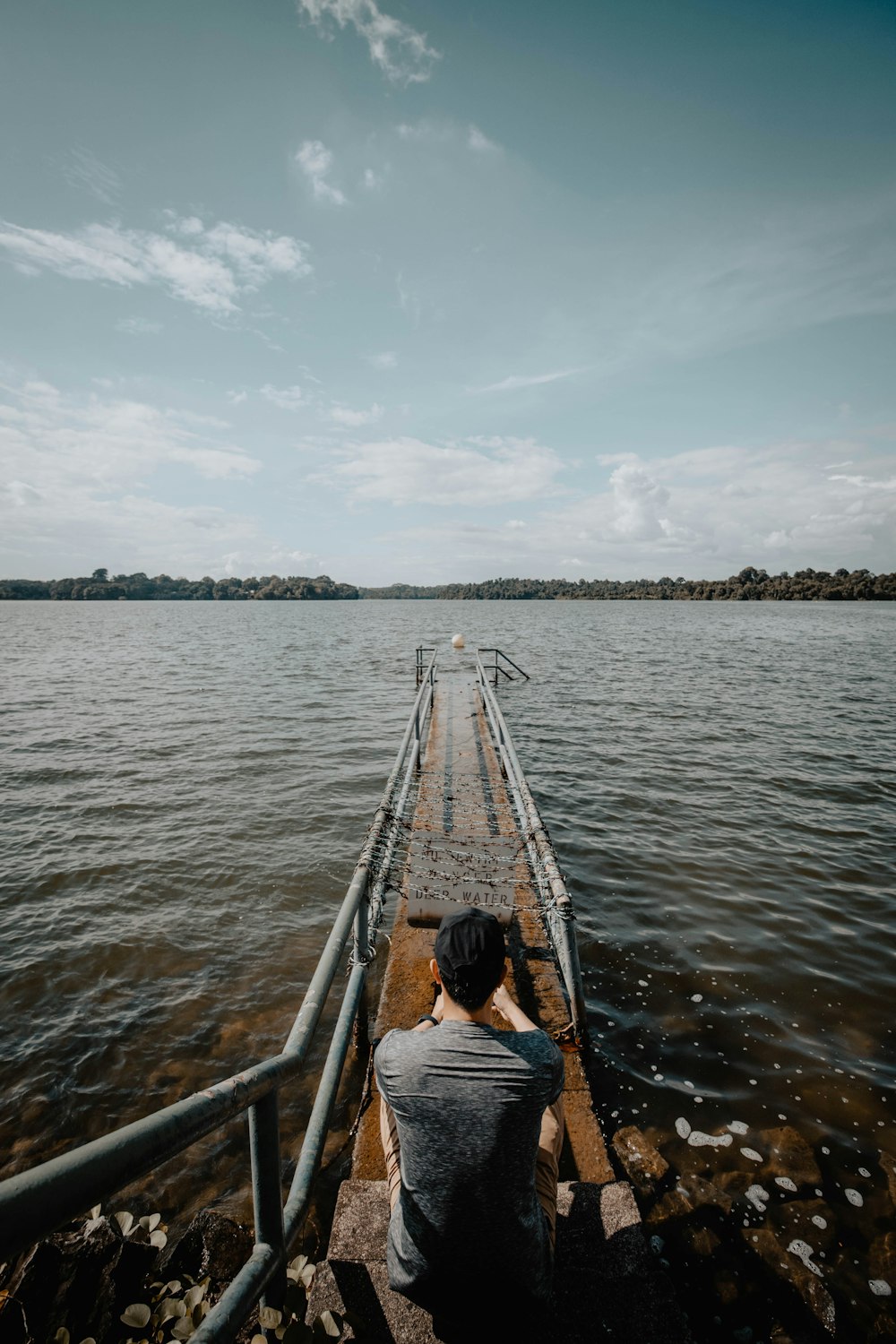 man sitting on small dock during daytime