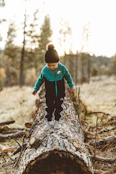 boy wearing jacket walking on tree trunk