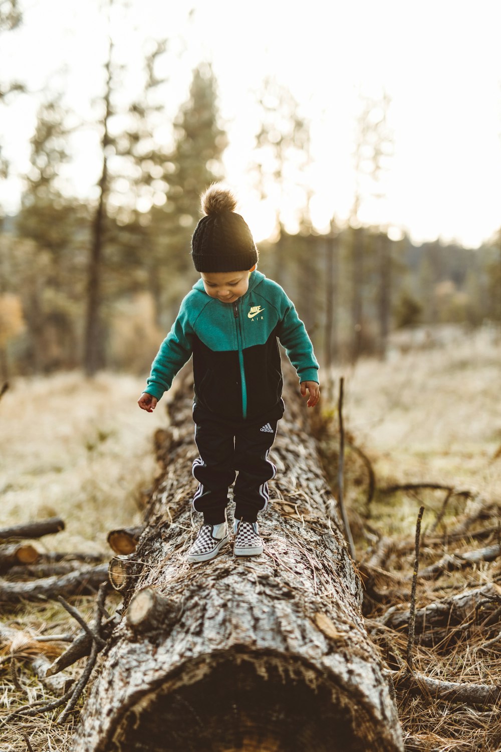 boy wearing jacket walking on tree trunk