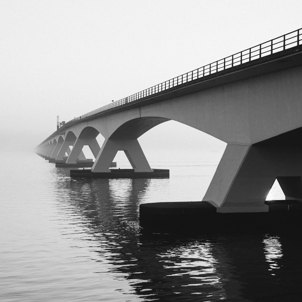 grayscale photography of bridge above water