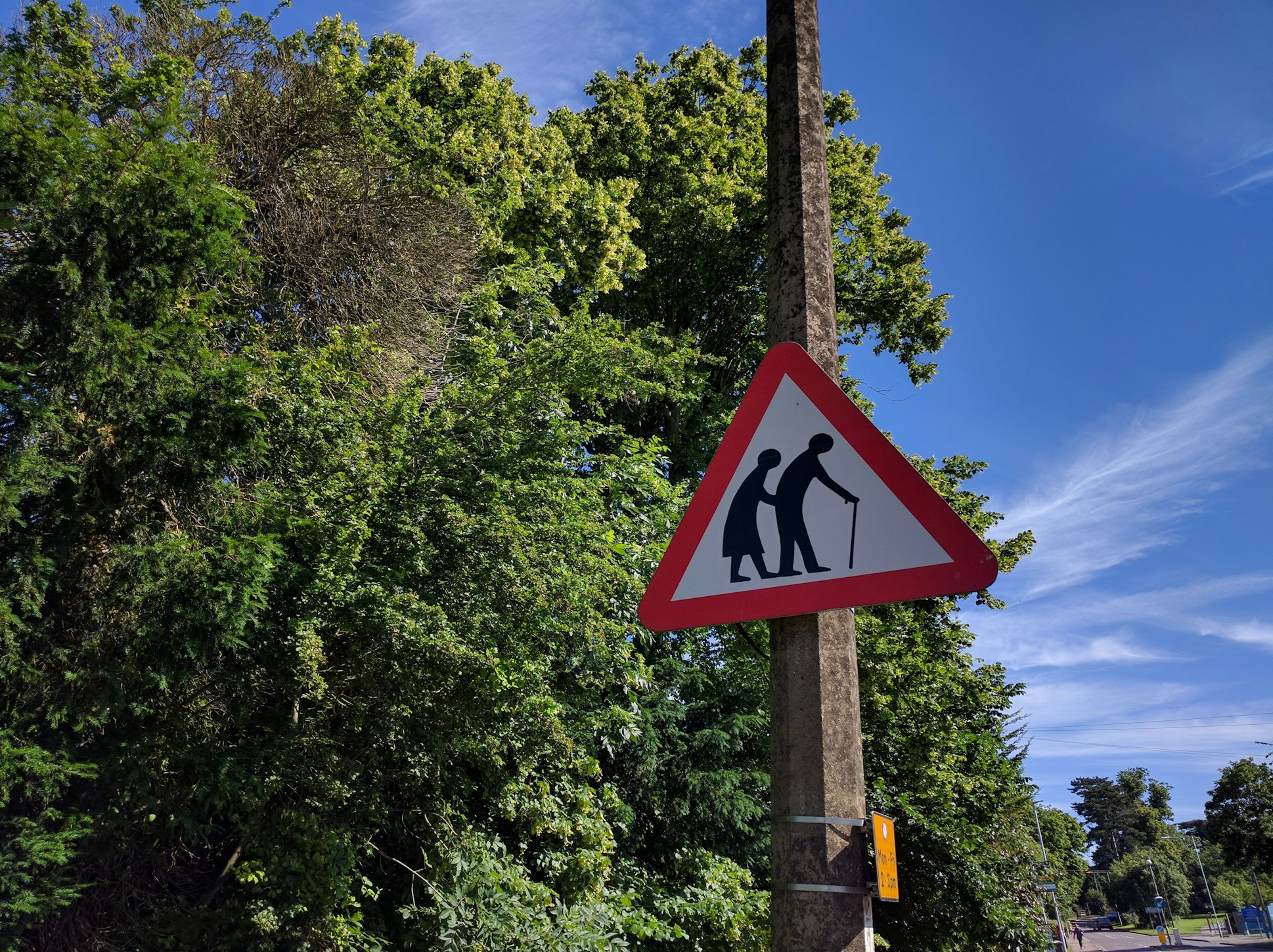 Bright sunny day with a suburbia street sign of "Please give way, elderly crossing" 