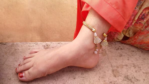 Close-up of elegant feet adorned with delicate ankle jewelry on a soft velvet background.