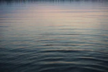 Gentle ripples on a serene mountain lake reflecting the early morning sky.