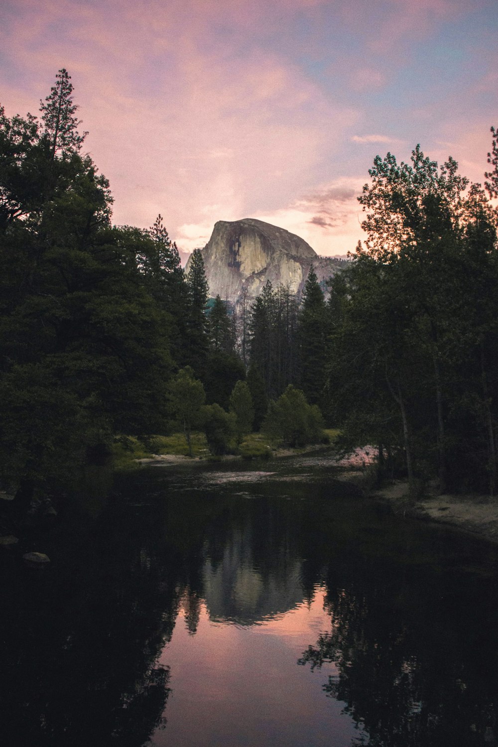 calm body of water near trees and mountain