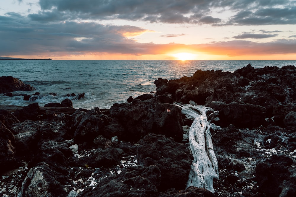 Formação rochosa marrom perto do mar durante o pôr do sol