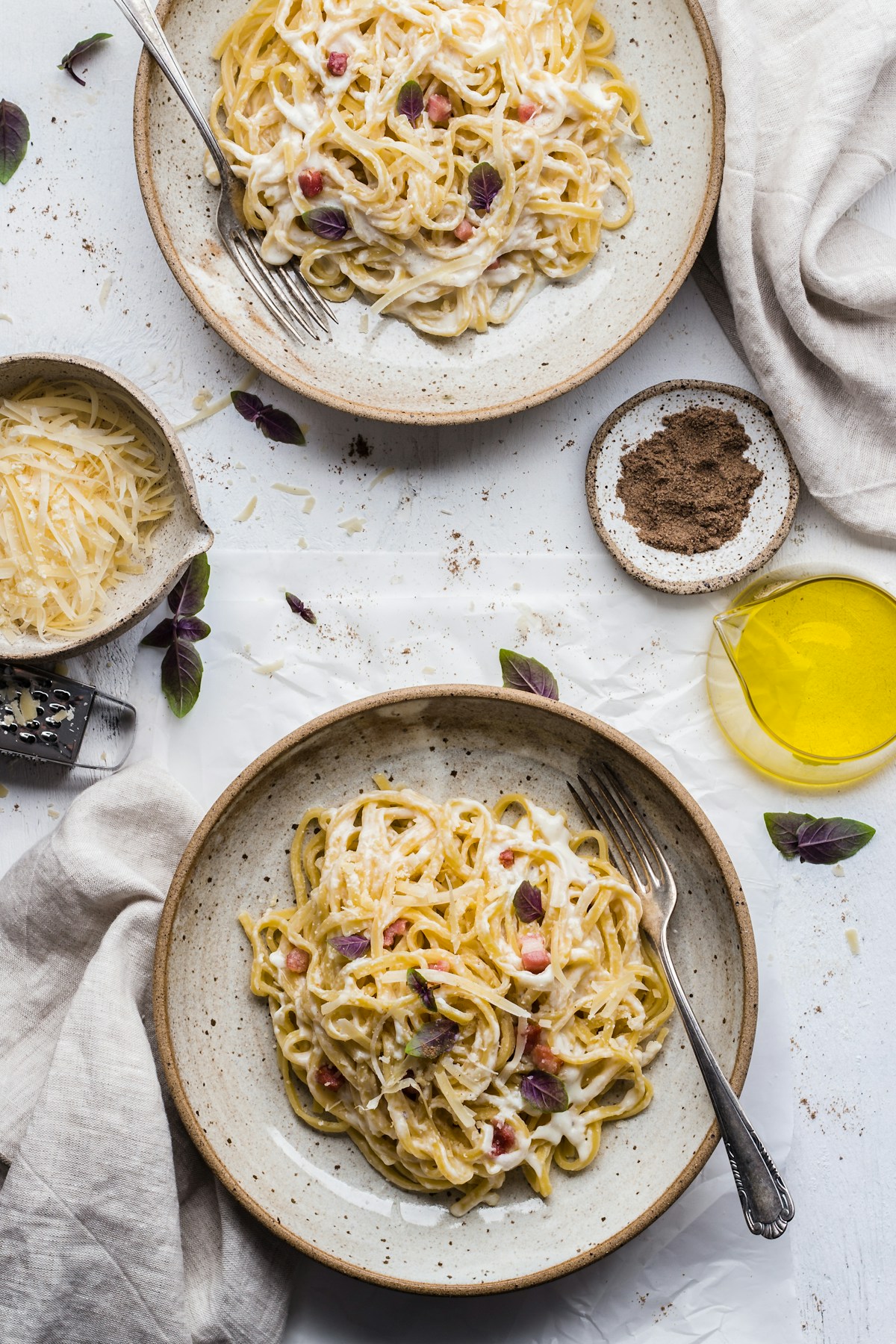 Spaghetti carbonara in a white bowl with black pepper and pecorino