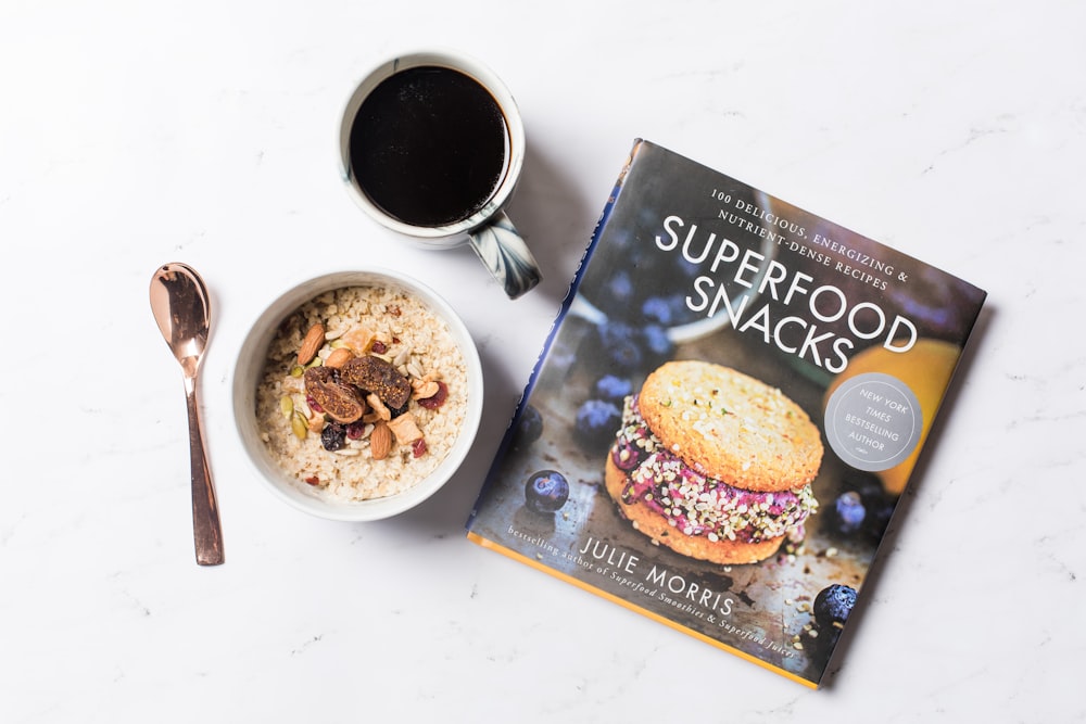flat lay photography of coffee, Superfood Snacks magazine, and bowl of cereals