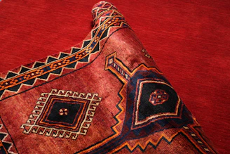A richly patterned Yoruba handwoven fabric in deep crimson and gold.