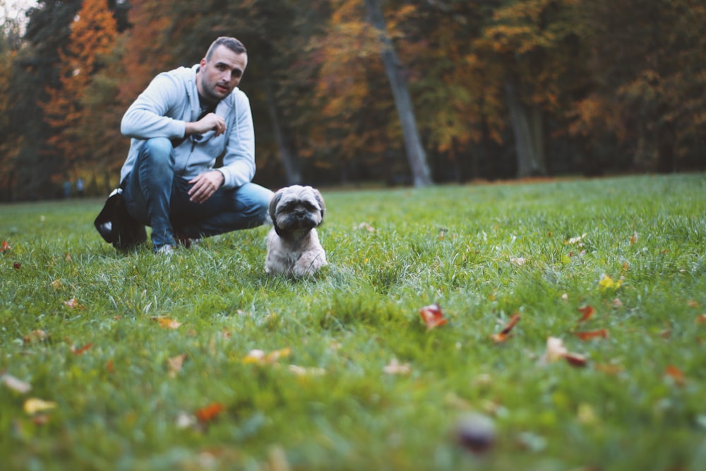 man on grass field near puppy during daytime