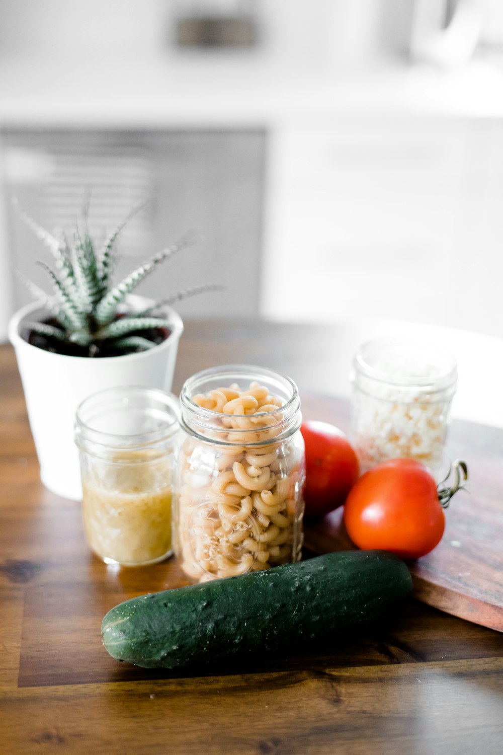 green cucumber near jars on table