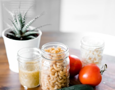 green cucumber near jars on table