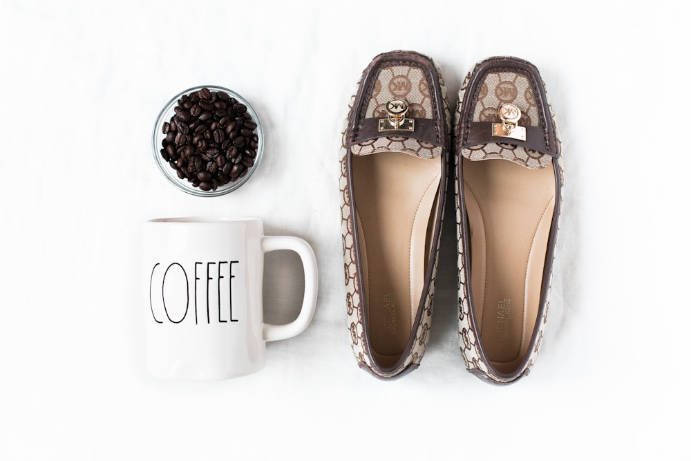 pair of brown flat shoes near mug