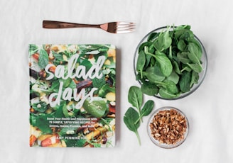 Salad day cookbook beside clear glass bowl with vegetable