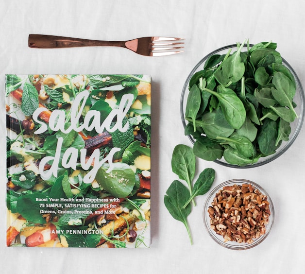 Salad day cookbook beside clear glass bowl with vegetable