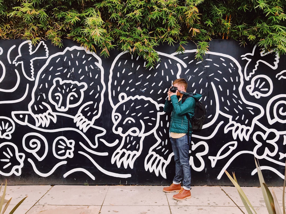 man taking photo while standing near wall