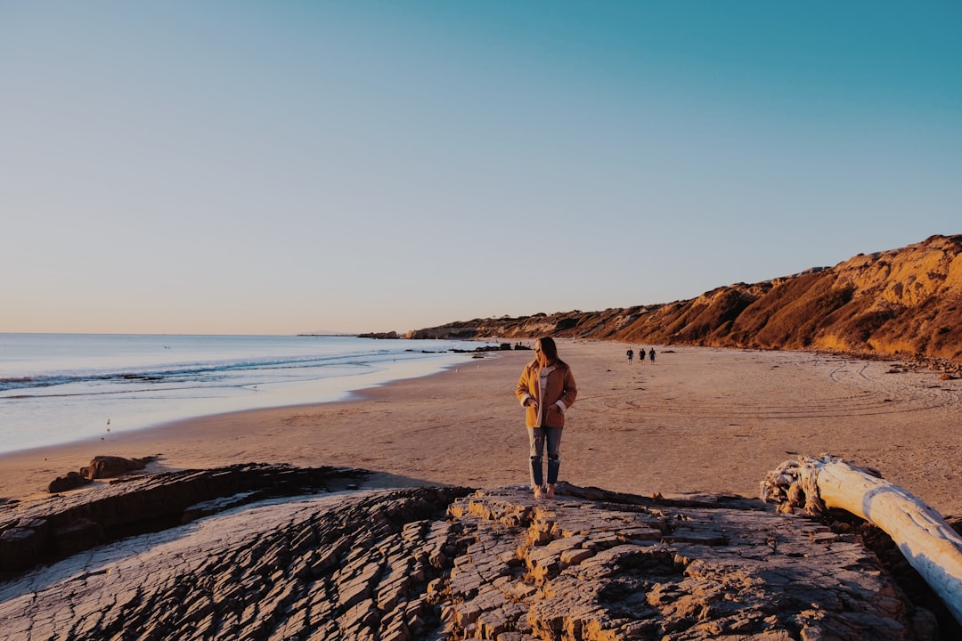 landscape photography of woman standing near seashore during daytime