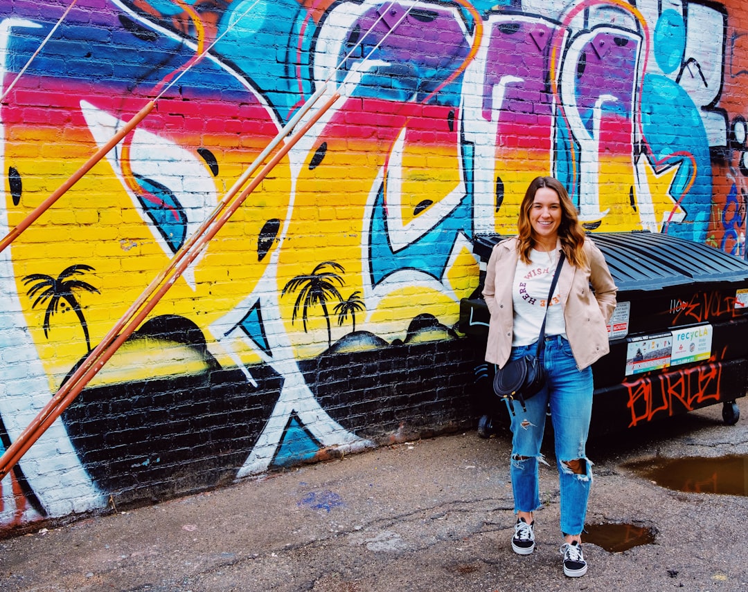 woman in blue jeans near graffiti wall