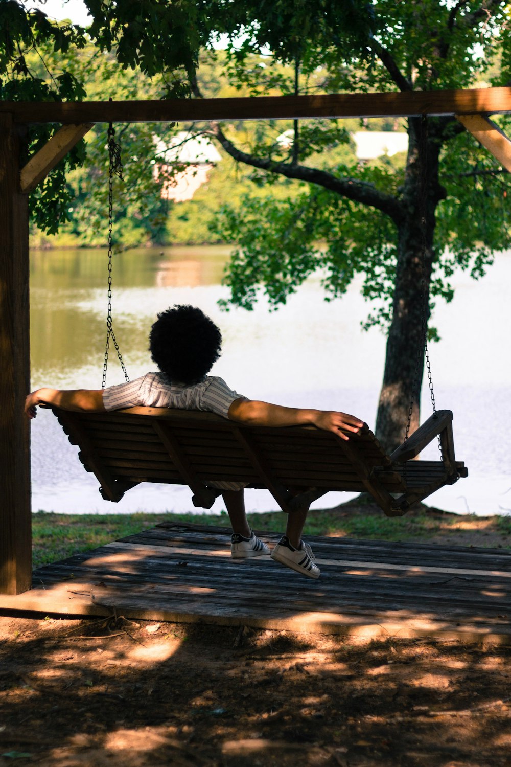 person sitting on hammock facing lake
