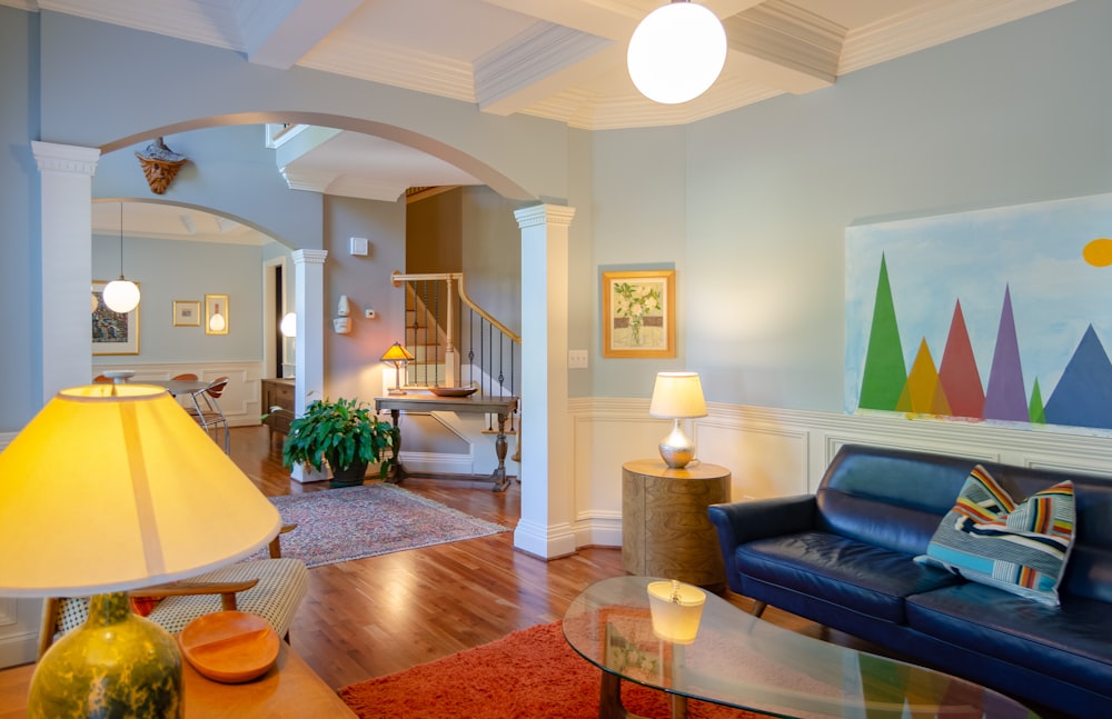 blue padded couch in front of glass-top center table