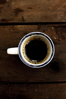 Close-up of a sleek, minimalist mug filled with steaming coffee on a wooden table.