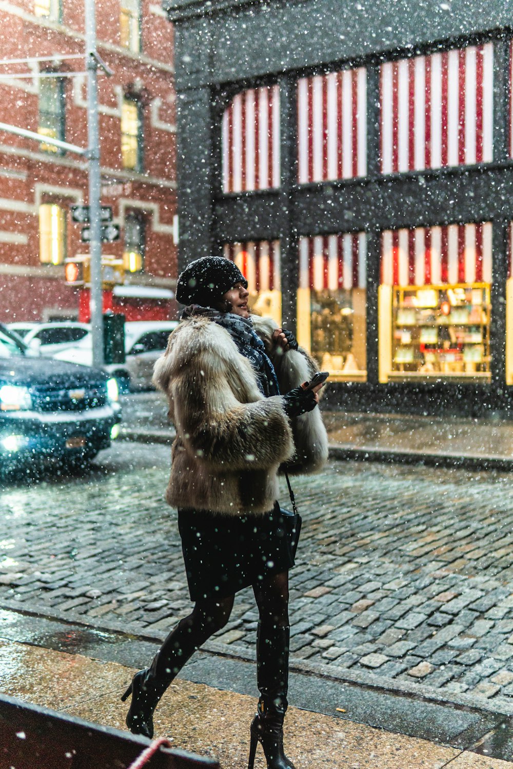 갈색 모피 코트를 입은 여자가 겨울철에 보도 산책을 걷고 있습니다.