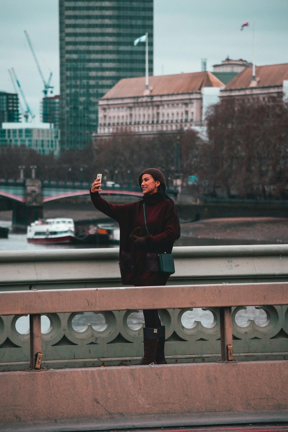 woman standing on bridge taking selfie