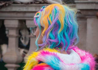 selective color photography of woman wearing blue, yellow, and pink coat and hair