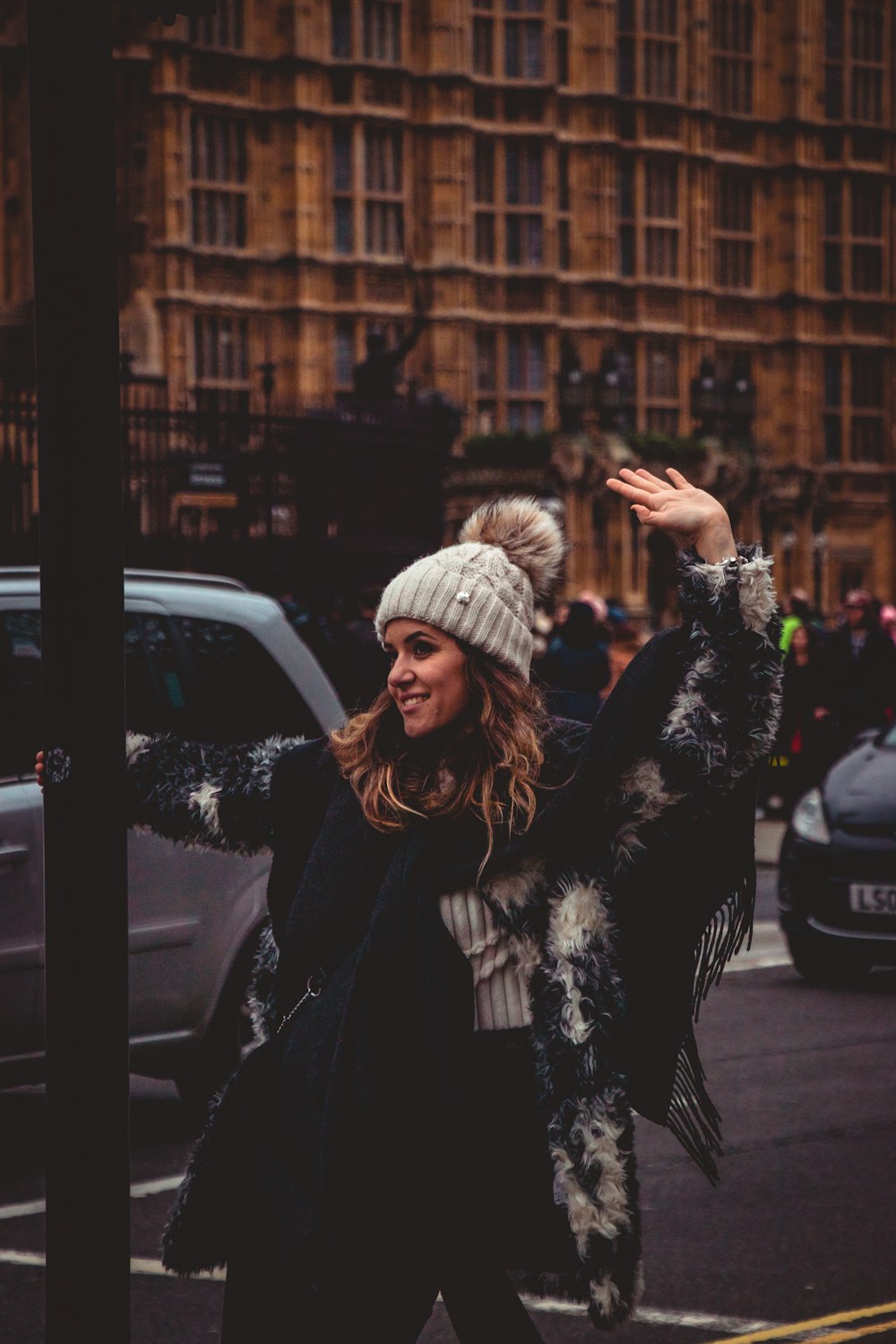 woman in black coat holding post