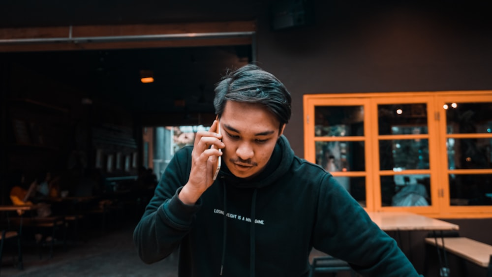 man using smartphone in black pullover hoodie