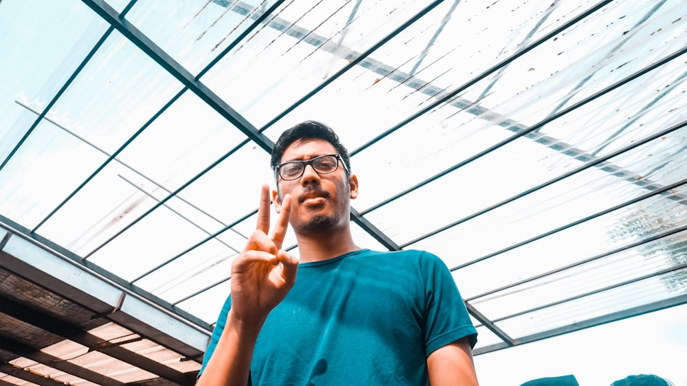 man wearing green t-shirt doing peace hand sign