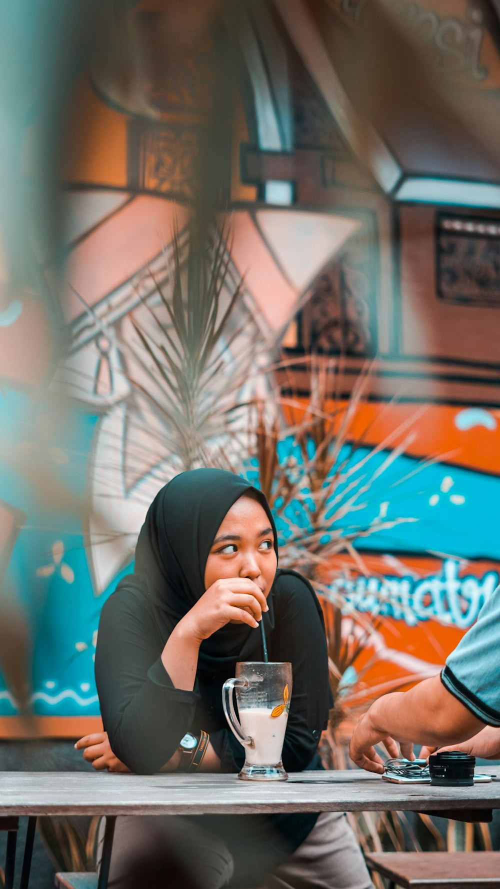 selective focus photography of woman in black hijab while drinking beverage