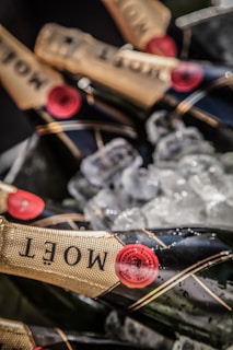 Several bottles of champagne are placed on ice, with labels featuring gold foil and red accents. The bottles partially submerged in ice give off a luxurious and celebratory vibe through the use of elegant design and chilled presentation.